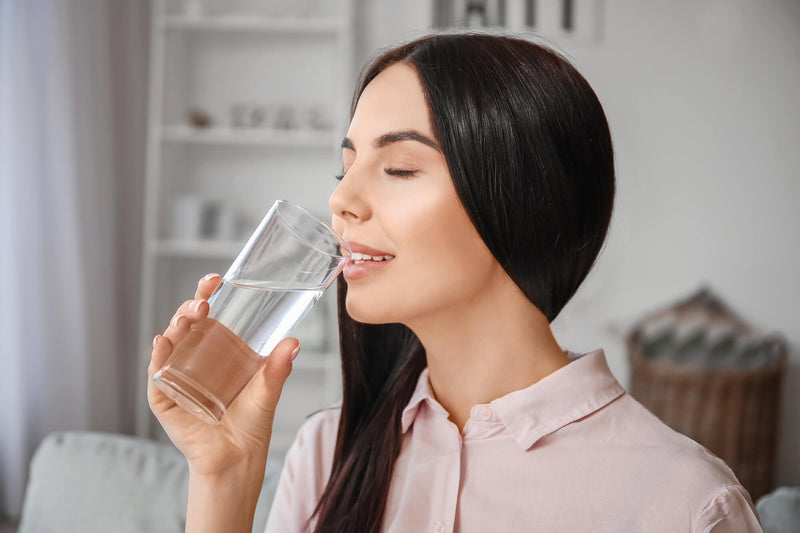 Beautiful young woman drinking water at home