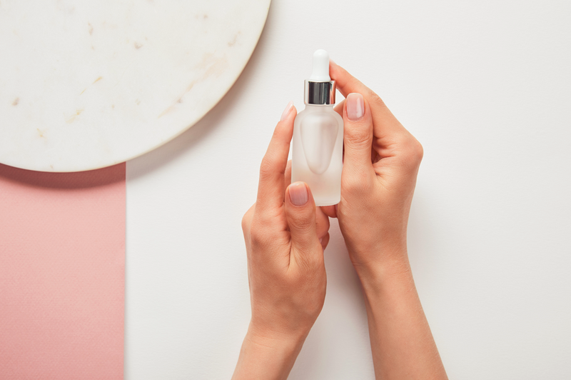 hand of a woman holding a niacinamide serum bottle