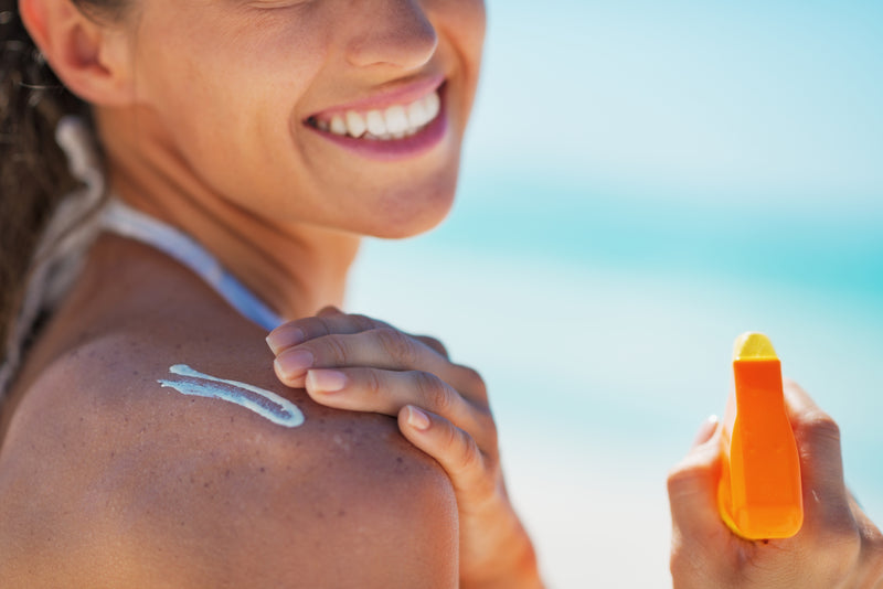 A happy young woman applying sunscreen