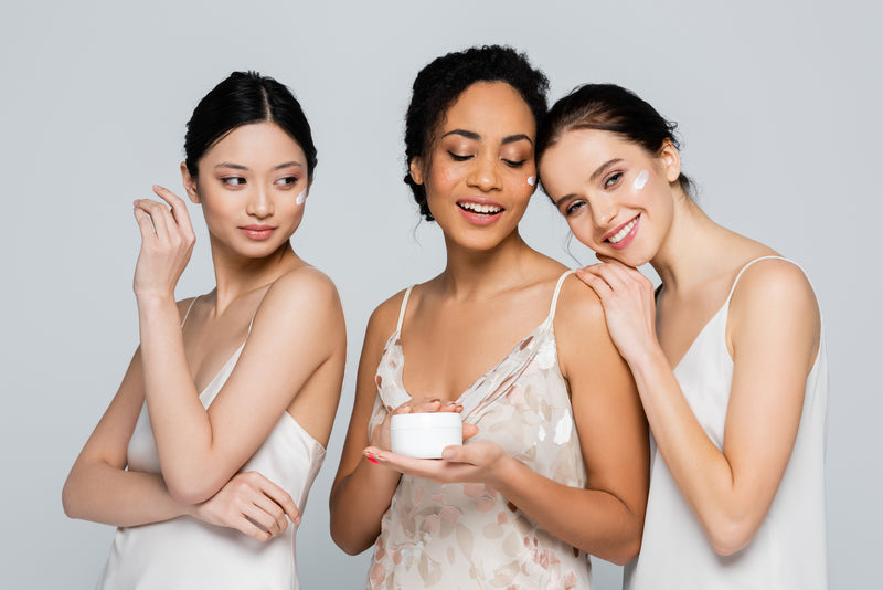 Three women holding skincare product