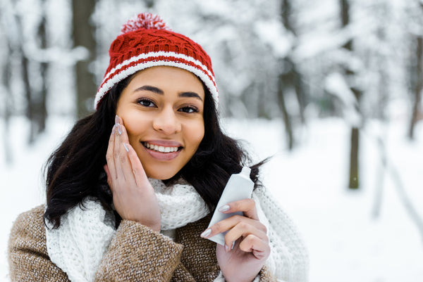 Woman applying skincare in her cheeks in winter forest