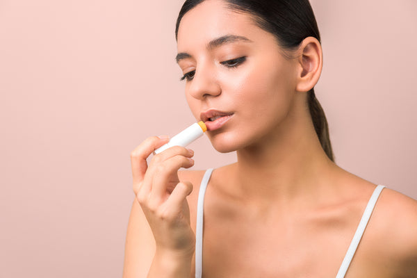 Woman doing her lip care routine by applying a lip balm