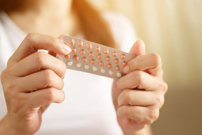 Woman holding a birth control pill